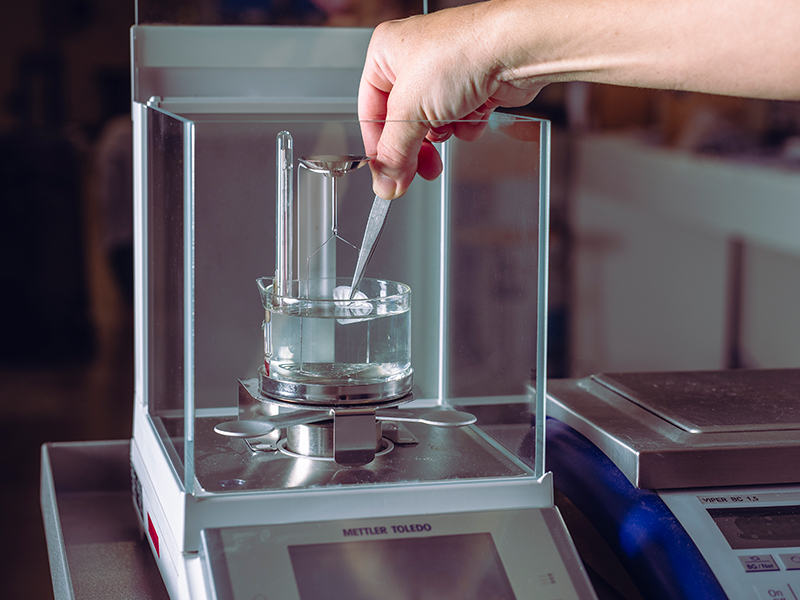 Pesatura di un campione su bilancia di precisione in laboratorio
